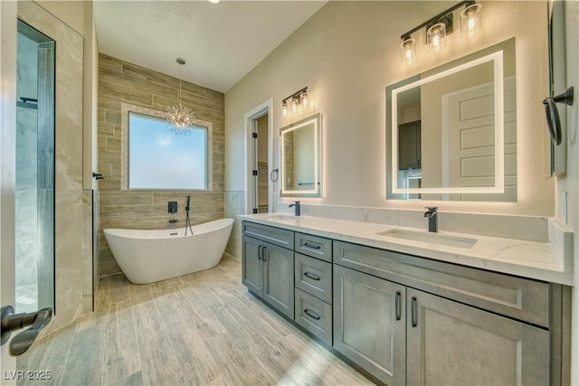 bathroom featuring tile walls, vanity, wood-type flooring, and a tub