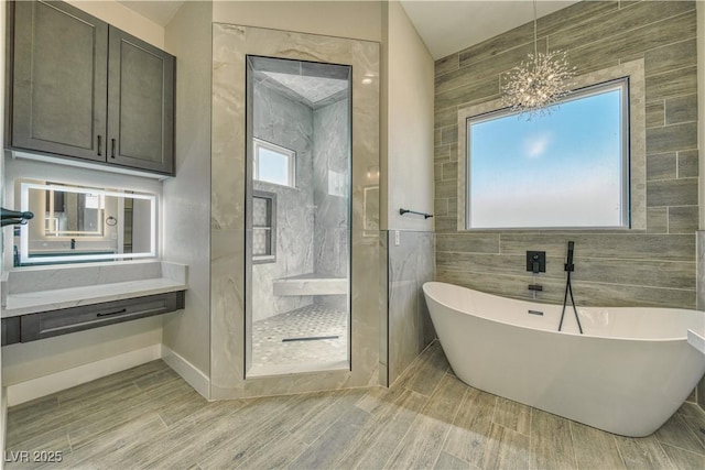 bathroom with plus walk in shower, tile walls, and a notable chandelier