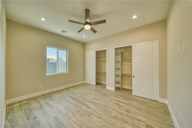 unfurnished bedroom with ceiling fan, two closets, and light wood-type flooring