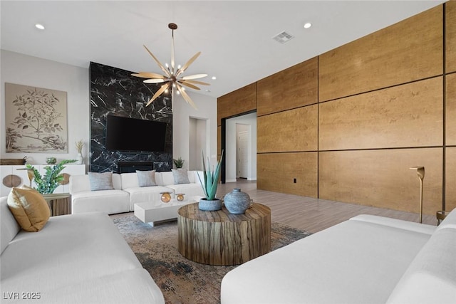 living room with hardwood / wood-style flooring, a premium fireplace, and a notable chandelier