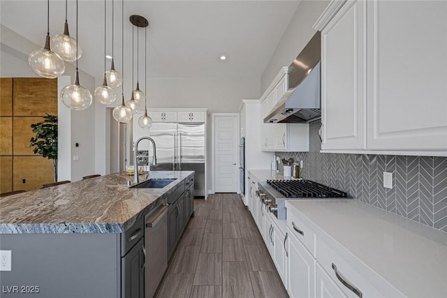 kitchen with a kitchen island with sink, sink, white cabinets, and pendant lighting