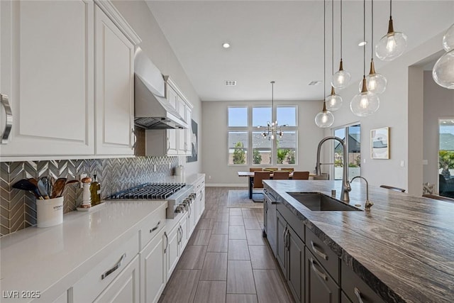 kitchen featuring pendant lighting, wall chimney exhaust hood, and white cabinetry