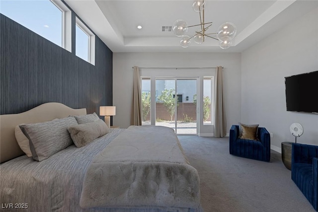 carpeted bedroom with access to outside, a tray ceiling, and a chandelier