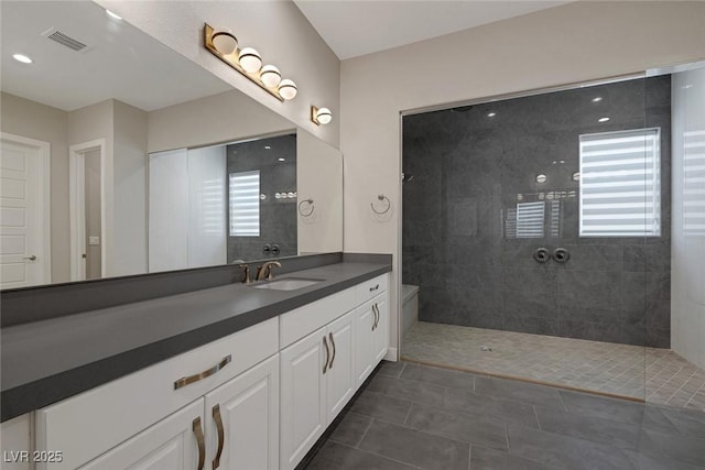 bathroom featuring tile patterned flooring, vanity, tiled shower, and a wealth of natural light