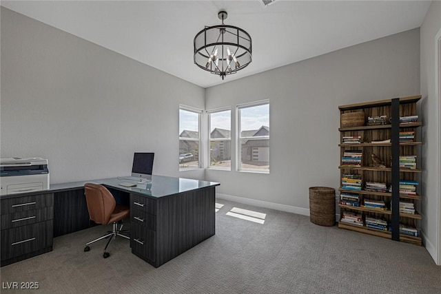 carpeted home office featuring a chandelier