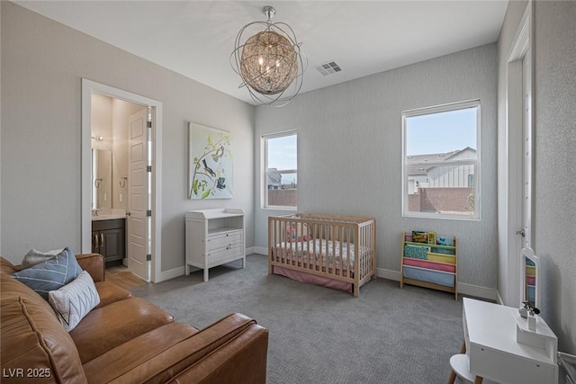 bedroom featuring ensuite bath, carpet floors, a chandelier, and a crib