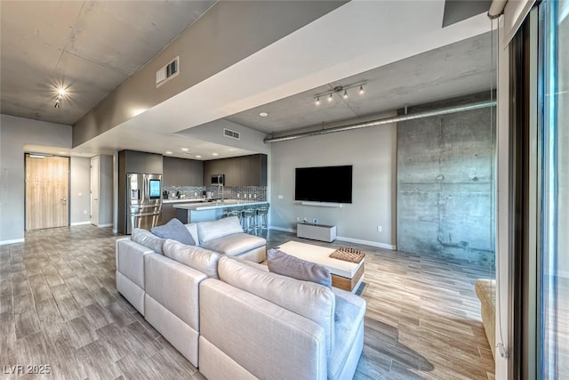 living room featuring rail lighting and light hardwood / wood-style flooring