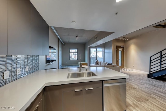 kitchen featuring kitchen peninsula, dishwasher, sink, and decorative backsplash