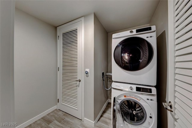 laundry room featuring light hardwood / wood-style floors and stacked washer / drying machine