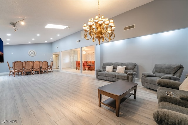 living room featuring light wood-type flooring, a high ceiling, and an inviting chandelier