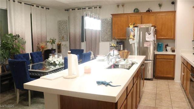 kitchen with stainless steel fridge, an island with sink, hanging light fixtures, and light tile patterned flooring