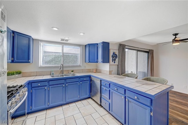 kitchen with kitchen peninsula, appliances with stainless steel finishes, blue cabinets, and sink