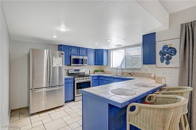 kitchen featuring kitchen peninsula, sink, blue cabinets, and appliances with stainless steel finishes