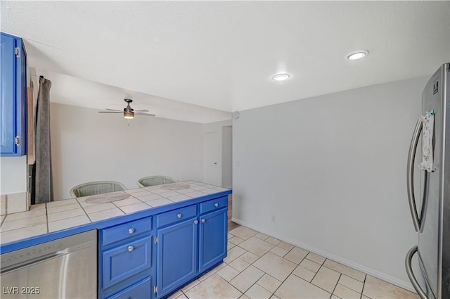 kitchen featuring ceiling fan, tile counters, blue cabinets, and appliances with stainless steel finishes