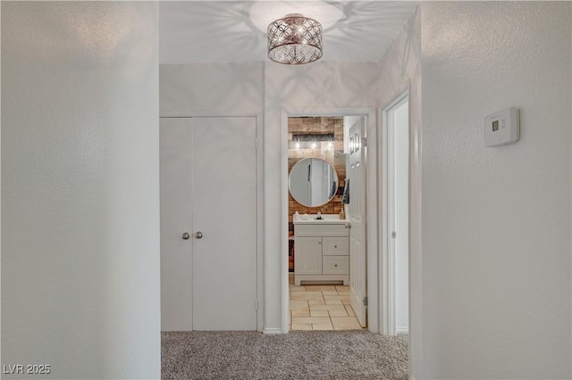 hallway with light colored carpet and sink