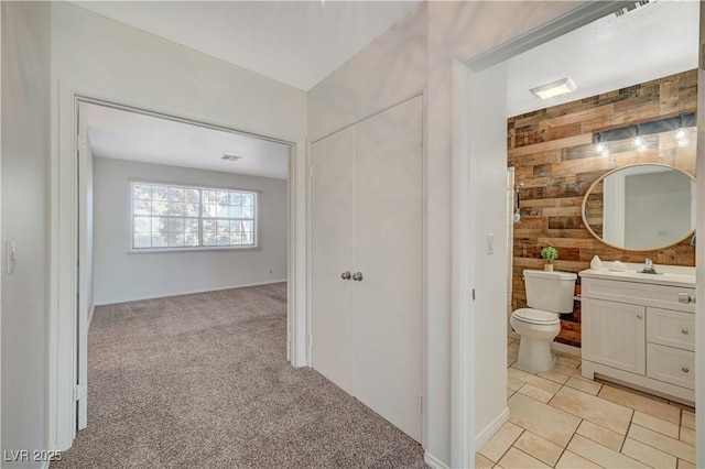 bathroom featuring tile patterned flooring, vanity, wood walls, and toilet