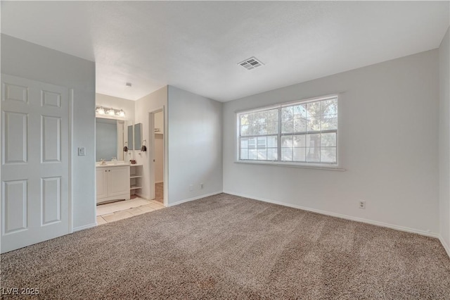 unfurnished bedroom with ensuite bath, light carpet, and sink