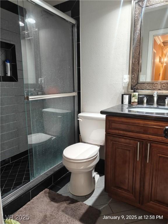 bathroom featuring tile patterned flooring, vanity, toilet, and walk in shower