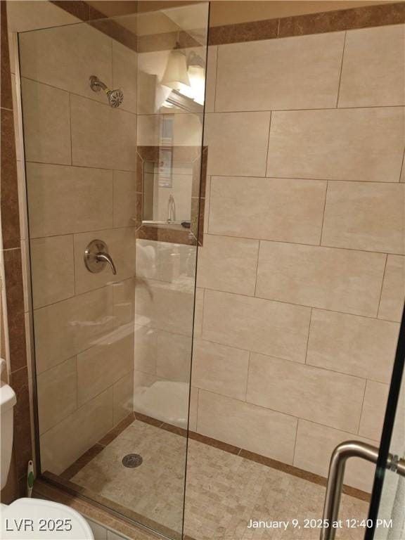 bathroom featuring toilet and a shower with shower door