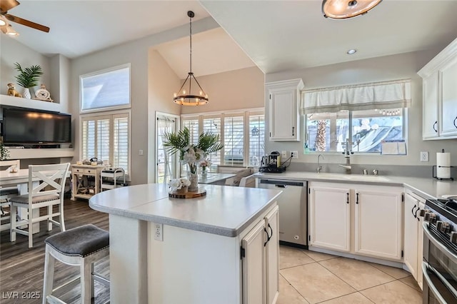 kitchen with sink, stainless steel appliances, pendant lighting, lofted ceiling, and white cabinets