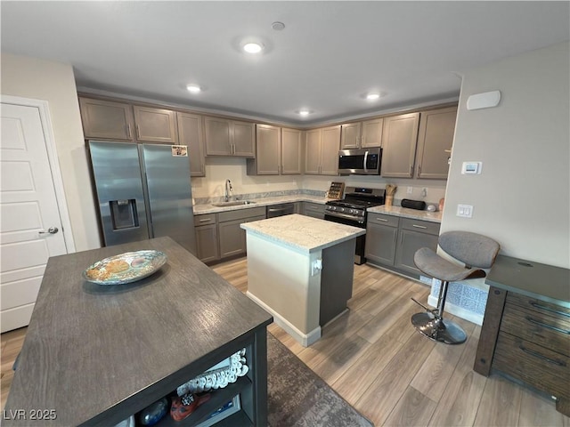 kitchen featuring gray cabinetry, sink, light hardwood / wood-style floors, a kitchen island, and appliances with stainless steel finishes