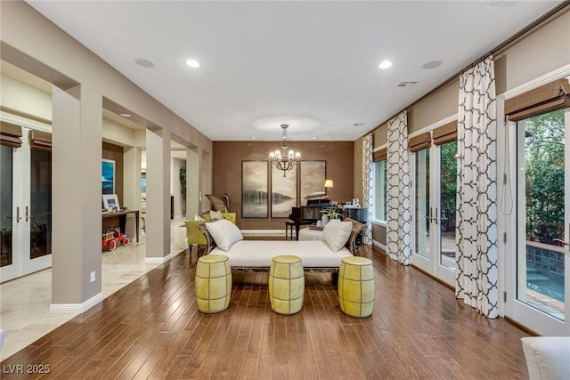 living room with hardwood / wood-style floors, french doors, and an inviting chandelier