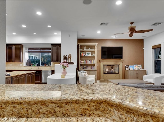 kitchen with ceiling fan, stainless steel dishwasher, light stone counters, and sink