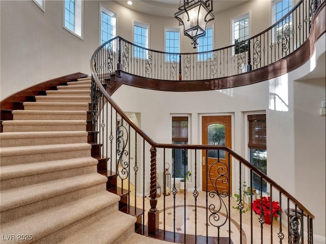 stairs with a high ceiling and a notable chandelier