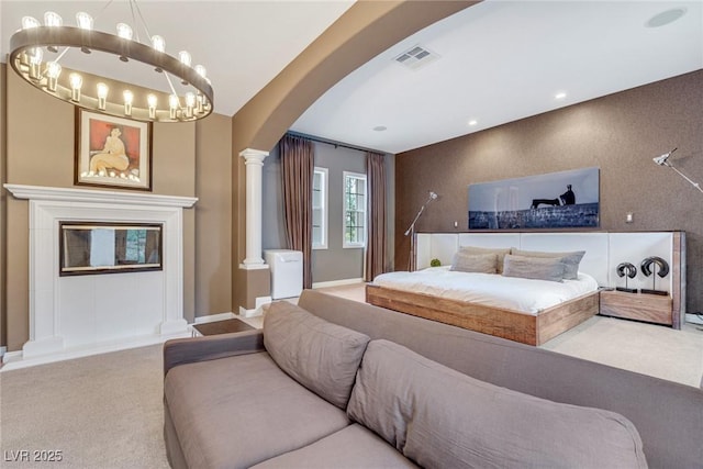 carpeted bedroom featuring decorative columns and an inviting chandelier