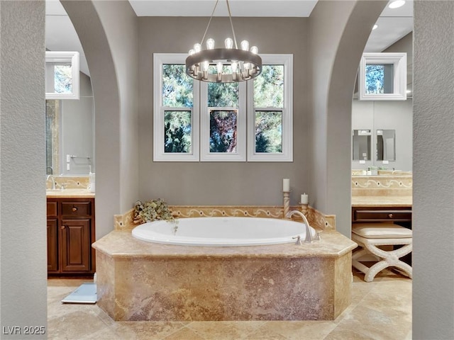 bathroom featuring vanity, an inviting chandelier, and tiled bath