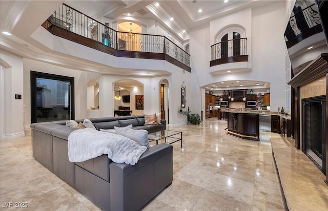 living room with a notable chandelier, ornamental molding, and a high ceiling