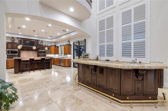 kitchen featuring a kitchen breakfast bar, light stone countertops, a large island, dark brown cabinets, and stainless steel appliances