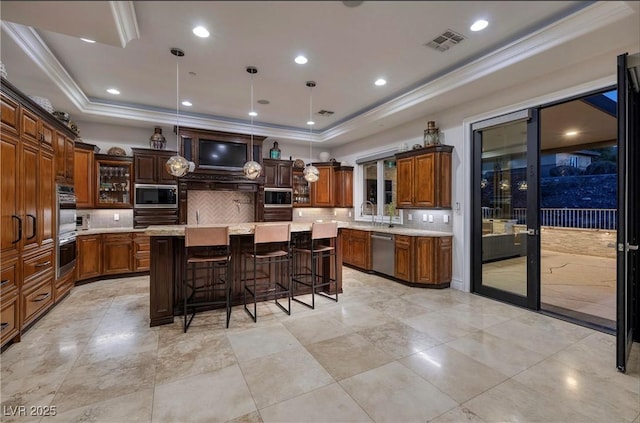 kitchen featuring backsplash, stainless steel appliances, a raised ceiling, decorative light fixtures, and a center island