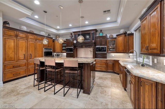 kitchen featuring pendant lighting, a center island, backsplash, a raised ceiling, and stainless steel appliances