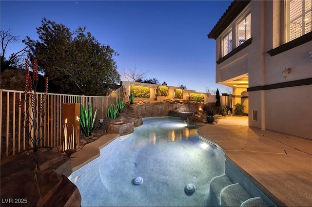 pool at dusk with a patio and a hot tub