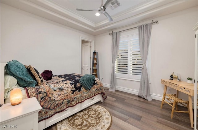 bedroom with a tray ceiling, ceiling fan, crown molding, and wood-type flooring