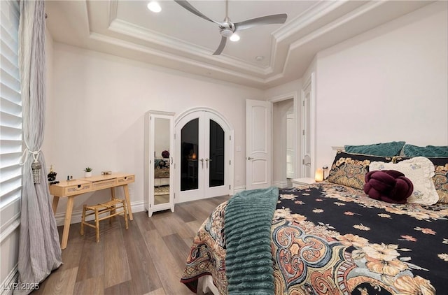 bedroom with hardwood / wood-style floors, french doors, crown molding, ceiling fan, and a tray ceiling