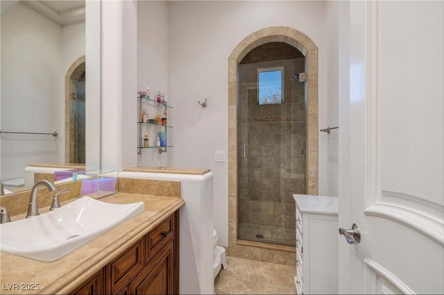 bathroom featuring tile patterned flooring, vanity, toilet, and walk in shower