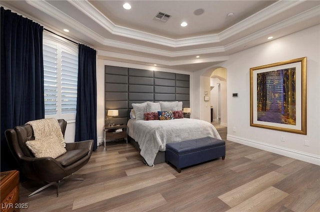 bedroom with hardwood / wood-style floors, crown molding, and a tray ceiling