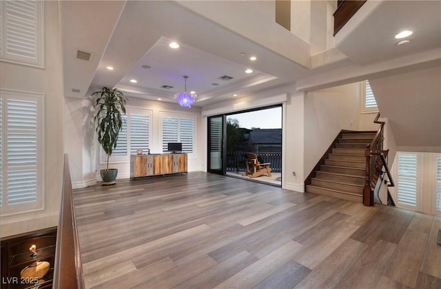 interior space with hardwood / wood-style floors, a raised ceiling, and an inviting chandelier