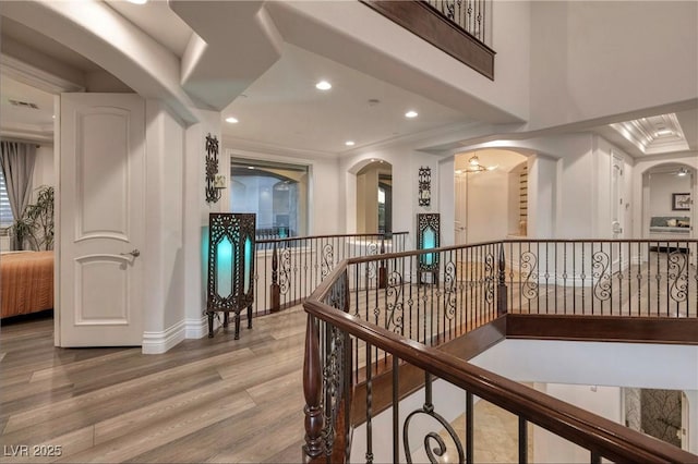 hallway with crown molding, wood-type flooring, and an inviting chandelier