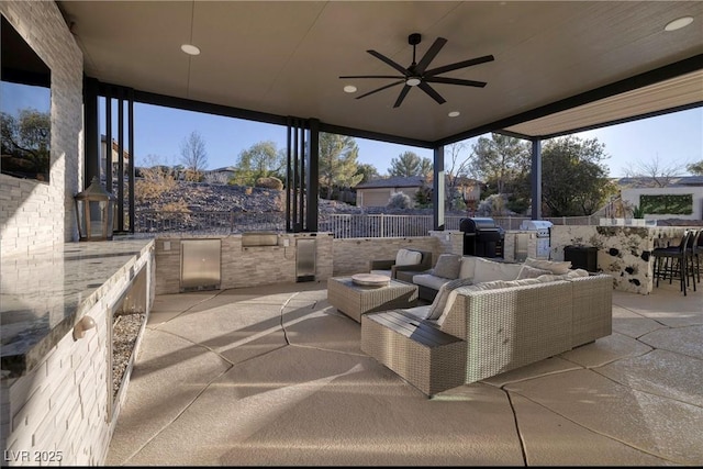 view of patio / terrace with an outdoor hangout area, an outdoor bar, ceiling fan, and exterior kitchen