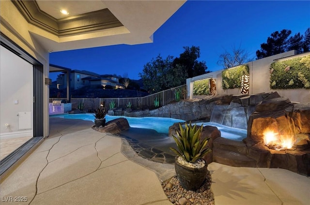 pool at twilight featuring pool water feature