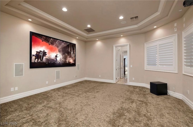 cinema room with a tray ceiling, crown molding, and carpet