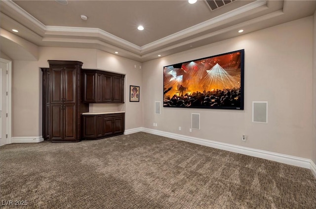 carpeted home theater room with ornamental molding and a tray ceiling