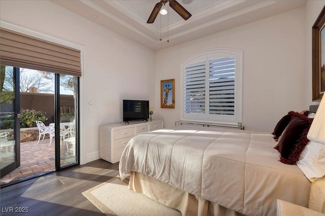 bedroom with access to exterior, dark hardwood / wood-style flooring, ornamental molding, a tray ceiling, and ceiling fan