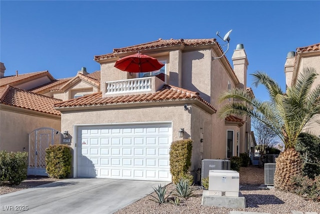 mediterranean / spanish home featuring an attached garage, central air condition unit, driveway, a tiled roof, and stucco siding