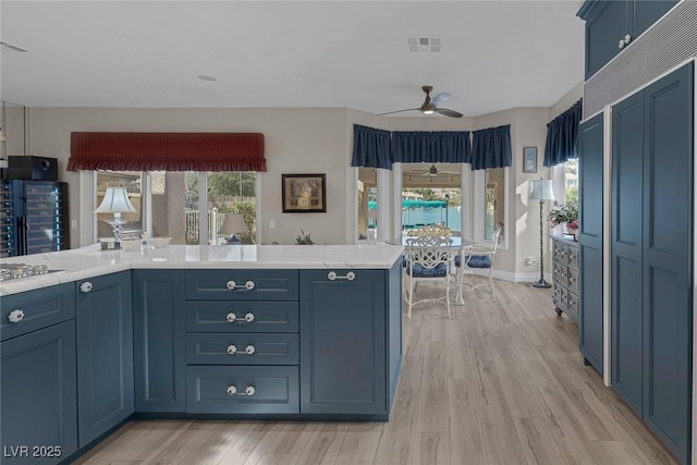 kitchen featuring light countertops, visible vents, a ceiling fan, blue cabinets, and light wood-type flooring