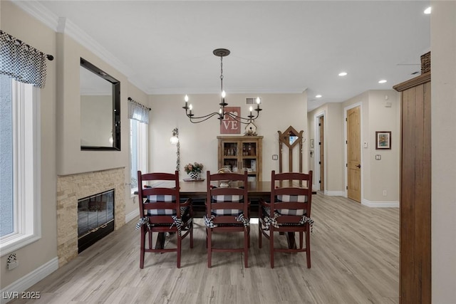 dining area with light wood-style floors, a fireplace, baseboards, and crown molding