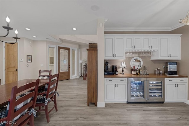 kitchen featuring beverage cooler, butcher block countertops, light wood-type flooring, and white cabinetry